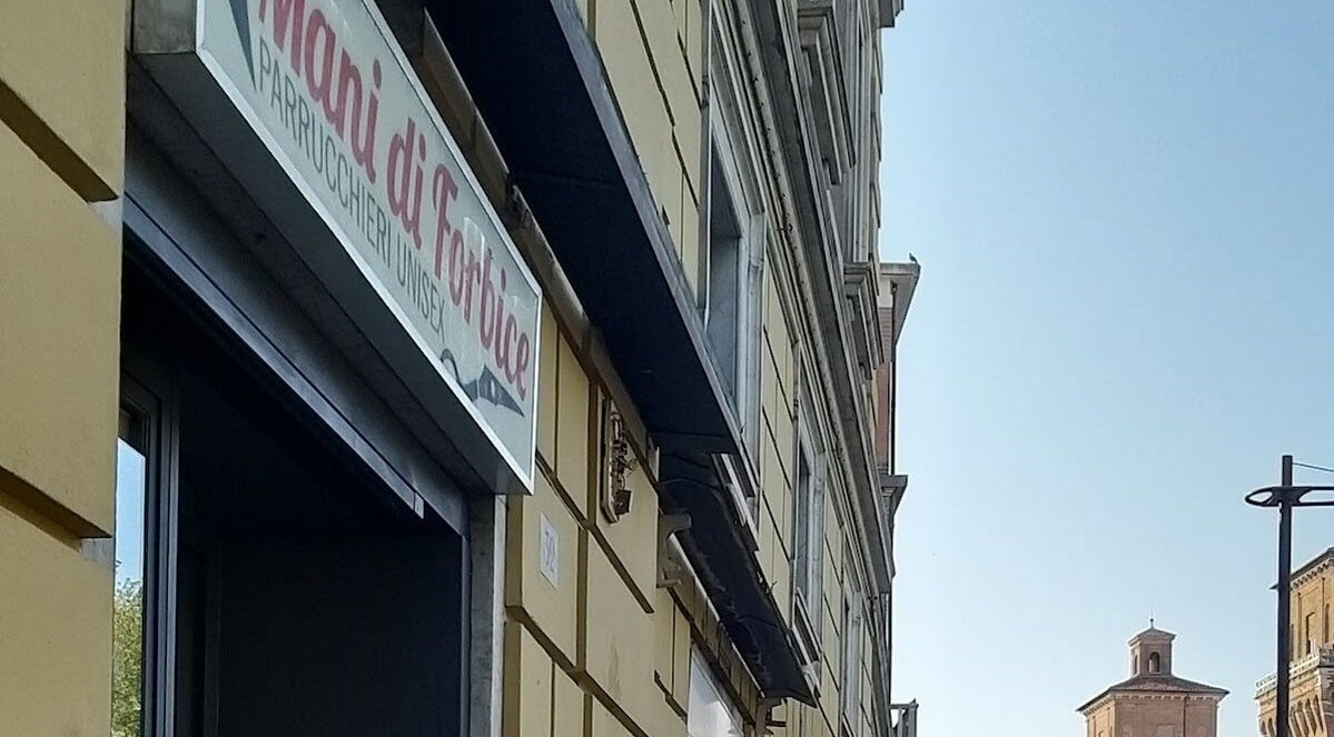 Insegna del salone Mani di Forbice a Ferrara, Emilia-romagna, IT con uno sfondo architettonico.