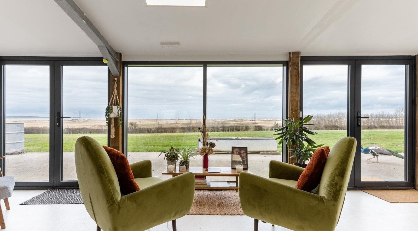 Cozy lounge at Joshua Rose Hair- Creative Space Kent in Faversham, England with panoramic countryside view.