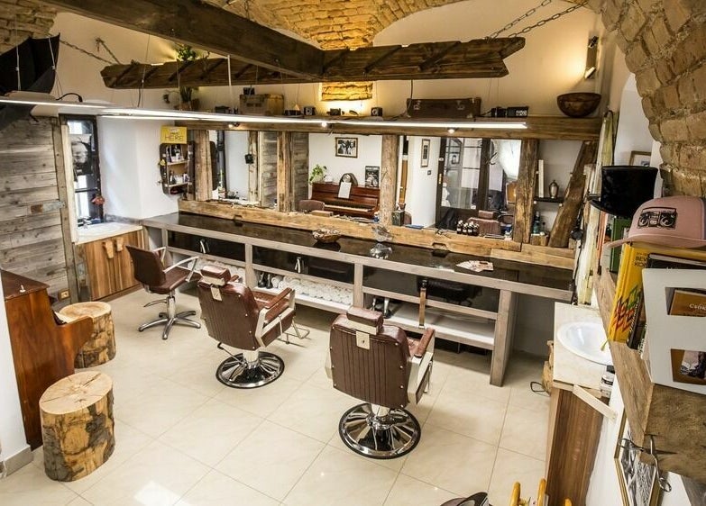 Fredy Barbershop Győr, HU: Meleg, rusztikus belső berendezés fa elemekkel és tágas tükörrel.
