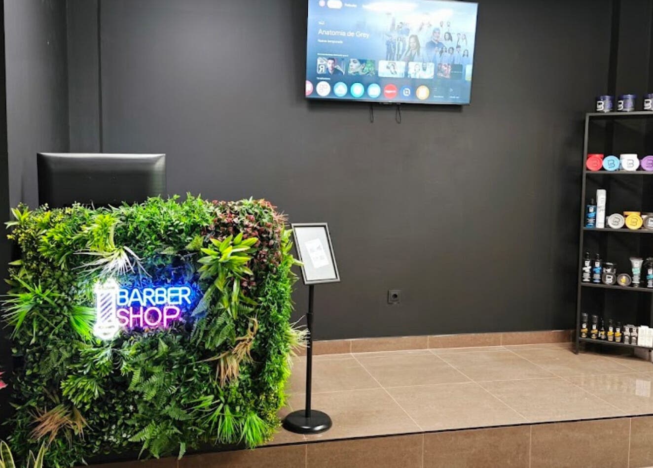 Recepción de Loro Bello Barbería en Móstoles, Comunidad De Madrid, ES, con un letrero de neón y plantas decorativas.