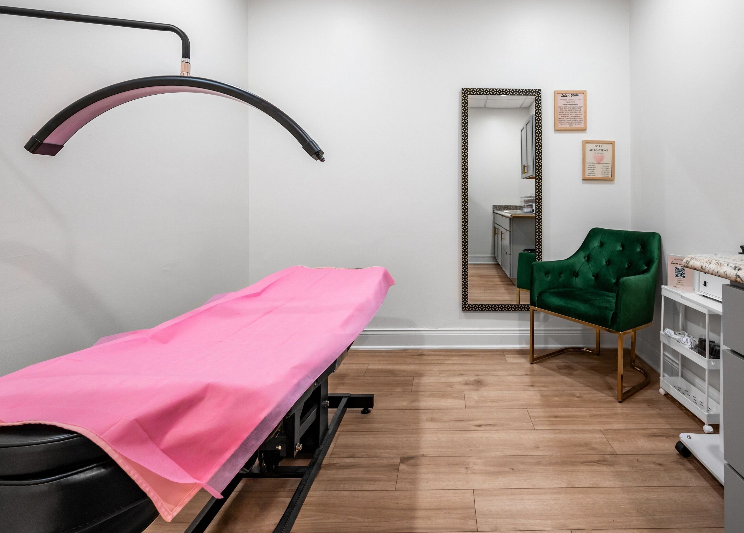 Chic treatment room at Artisan Theory Salon, Villa Park, Illinois, US with pink bed cover and green chair.