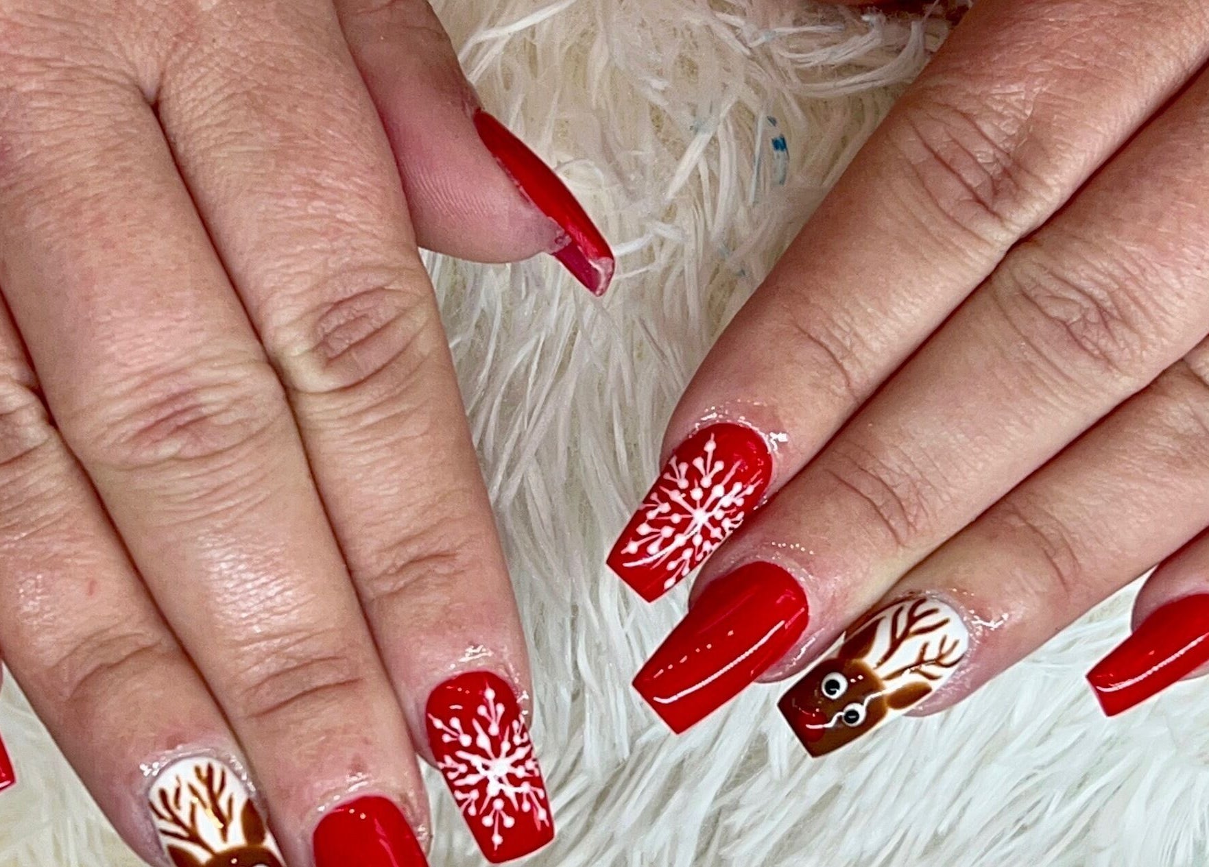 Festive red nails with snowflakes and reindeer art at Castle Nails and Spa Inc, Tewksbury, Massachusetts, US.