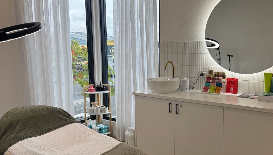 Elegant treatment room at Defined Cosmetics in Labrador, Queensland, AU, featuring a plush bed and mirrored decor.