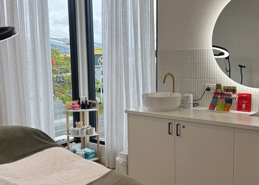 Elegant treatment room at Defined Cosmetics in Labrador, Queensland, AU, featuring a plush bed and mirrored decor.