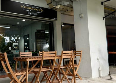 Outdoor view of Scissors Society's modern entrance in Singapore, Singapore, SG with wooden seating.