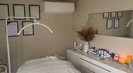Cozy treatment room at Skin.cetra, Guildford, England, GB featuring skincare products and certificates.