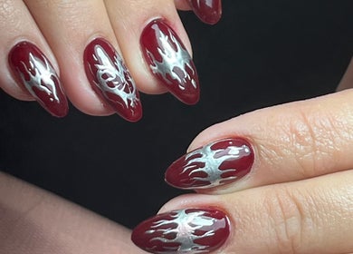Diseño de uñas rojo oscuro con detalles plateados en Miradas en ti, Bogotá, Bogotá, CO.