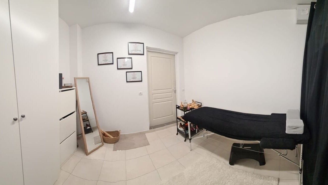 Salle de soins épurée à Maderolympe, Pringy, Île-de-France, FR avec table de massage et décor minimaliste.