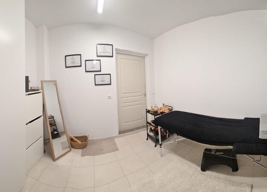 Salle de soins épurée à Maderolympe, Pringy, Île-de-France, FR avec table de massage et décor minimaliste.