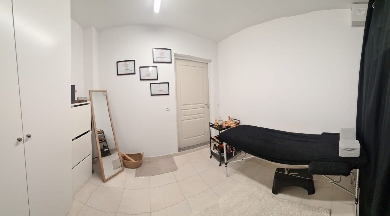 Salle de soins épurée à Maderolympe, Pringy, Île-de-France, FR avec table de massage et décor minimaliste.