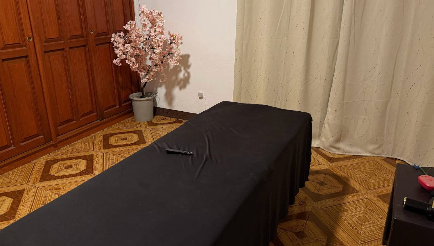 Sala de masajes en Kalize, Oaxaca De Juárez, Oaxaca, MX, con mesa cubierta y árbol de flor en esquina.