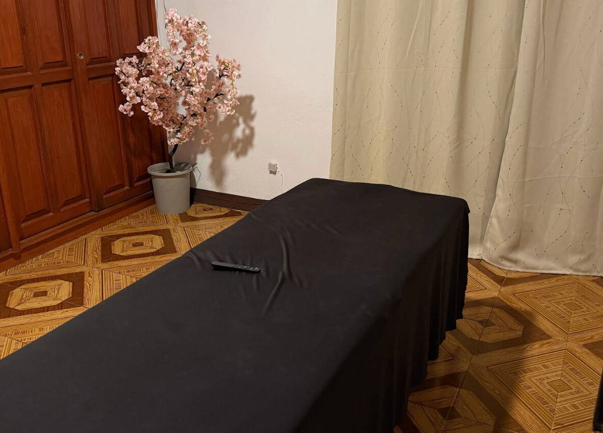 Sala de masajes en Kalize, Oaxaca De Juárez, Oaxaca, MX, con mesa cubierta y árbol de flor en esquina.