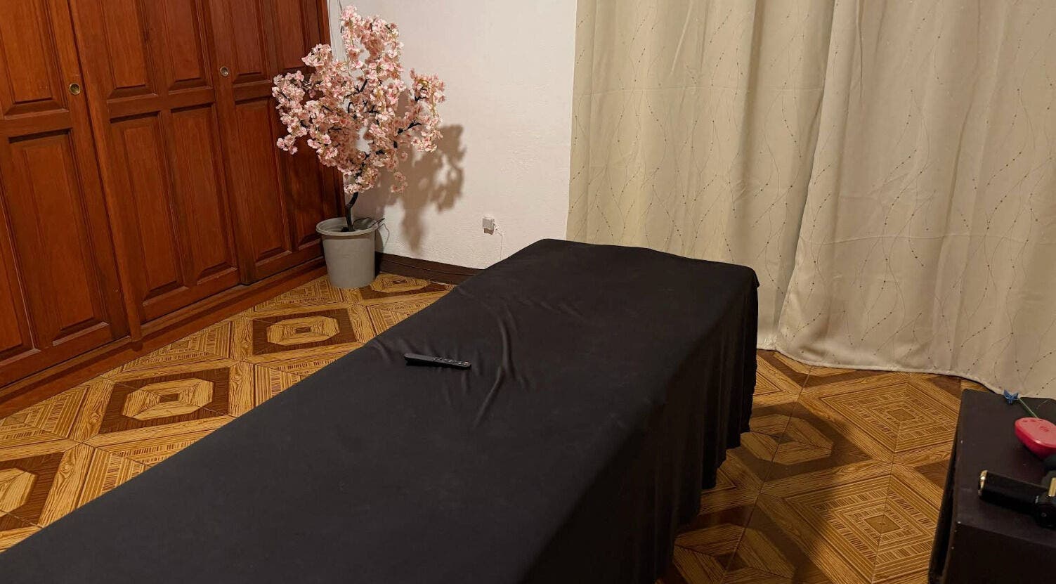 Sala de masajes en Kalize, Oaxaca De Juárez, Oaxaca, MX, con mesa cubierta y árbol de flor en esquina.