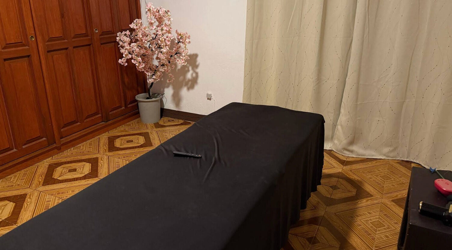 Sala de masajes en Kalize, Oaxaca De Juárez, Oaxaca, MX, con mesa cubierta y árbol de flor en esquina.
