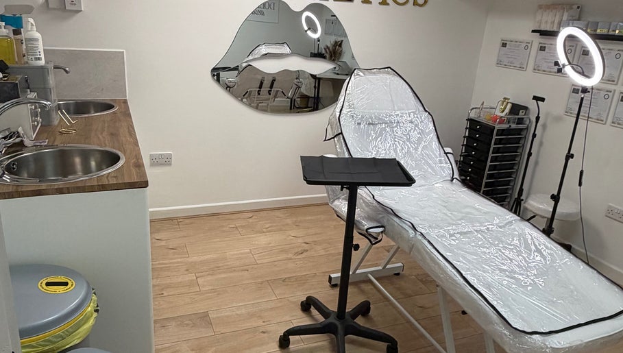 Modern treatment room at Doll’s House Aesthetics, Cwmbran, Wales, GB, with a stylish chair and chic decor.