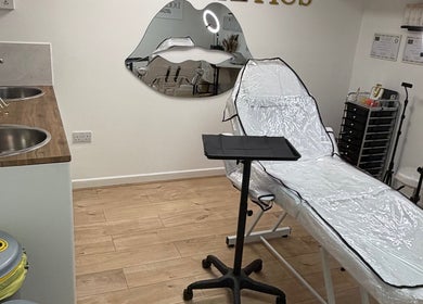 Modern treatment room at Doll’s House Aesthetics, Cwmbran, Wales, GB, with a stylish chair and chic decor.