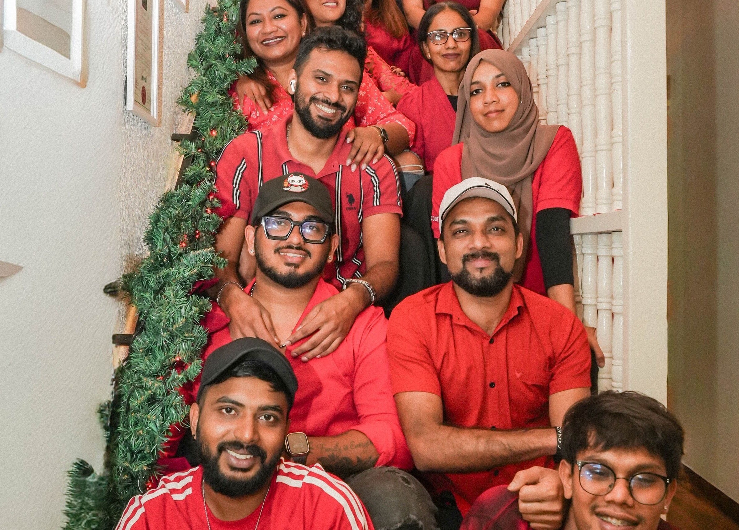 Team gathering on decorated staircase at Leena Hari, Colombo, Western Province, LK, celebrating in vibrant attire.