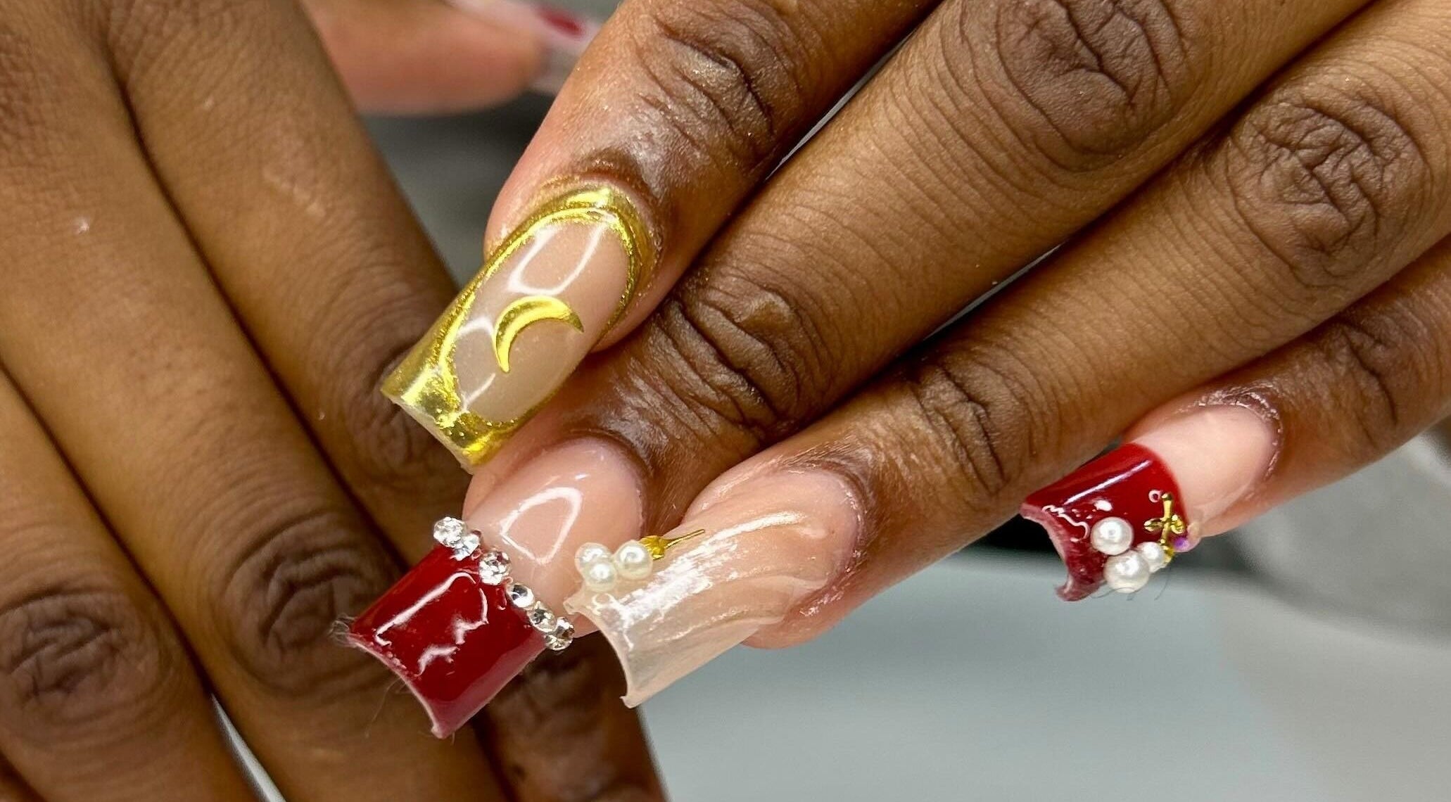 Intricate nail art featuring gold and red designs at The Aphentus in Witpoortjie, Gauteng, ZA.