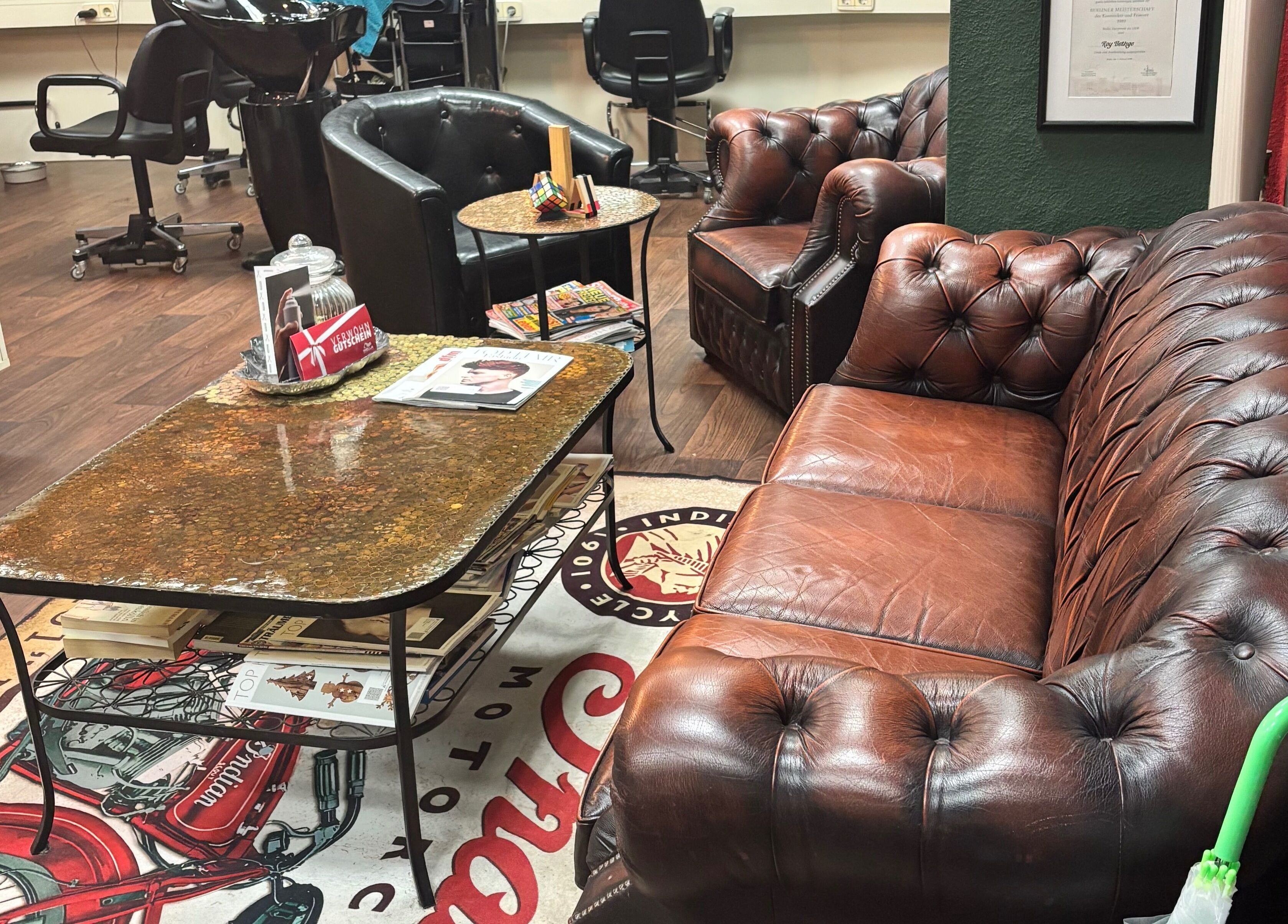 Gemütlicher Wartebereich bei Roy's Friseurteam in Berlin, Berlin, DE mit Ledersofas und stilvollen Möbeln.