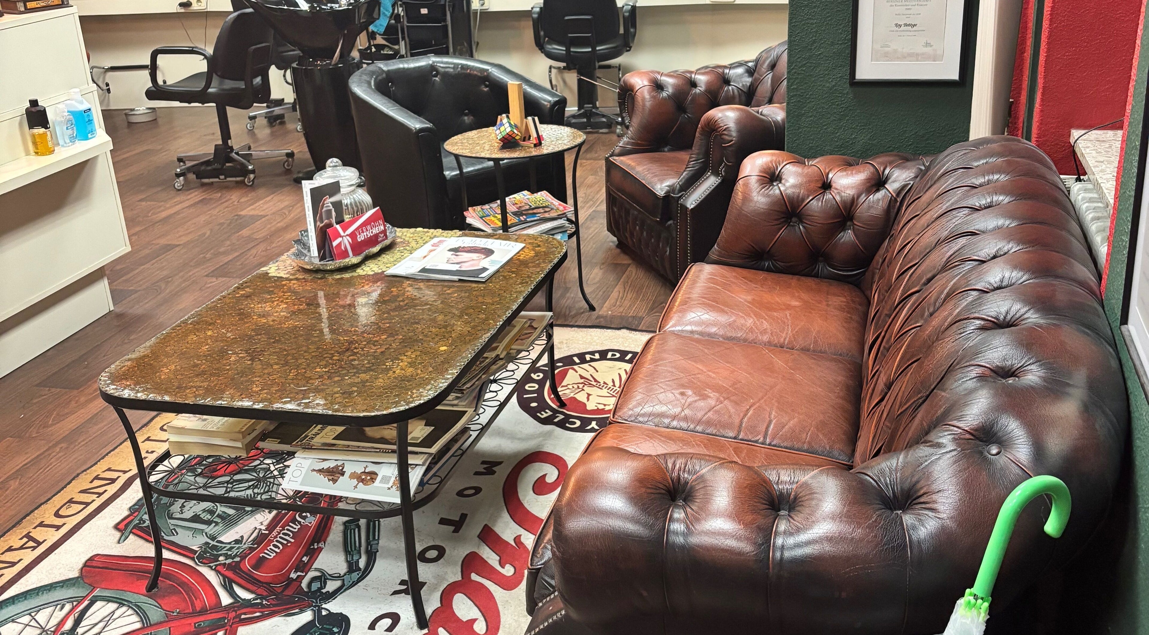 Gemütlicher Wartebereich bei Roy's Friseurteam in Berlin, Berlin, DE mit Ledersofas und stilvollen Möbeln.