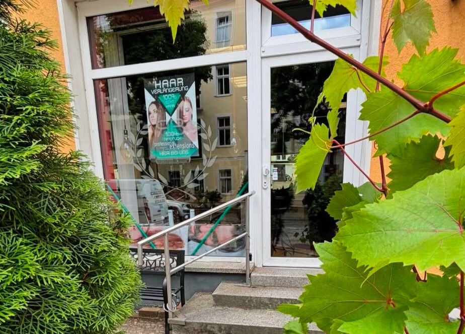 Haupteingang von Roy‘s Friseurteam umgeben von grünen Pflanzen in Berlin, Berlin, DE.