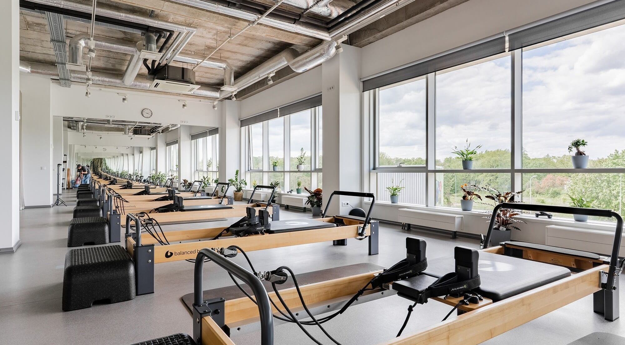 Spacious Pilates studio at FIZIO LINE, Rīga, LV, with bright windows and modern equipment.