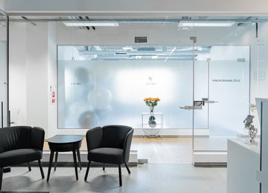 Modern lounge in FIZIO LINE, Rīga, LV featuring black armchairs and a glass door with floral decor.