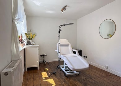 Bright, tranquil treatment room at Rare Aesthetics UK in Brighton And Hove, GB, featuring a cozy chair and mirror.