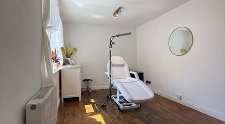 Bright, tranquil treatment room at Rare Aesthetics UK in Brighton And Hove, GB, featuring a cozy chair and mirror.