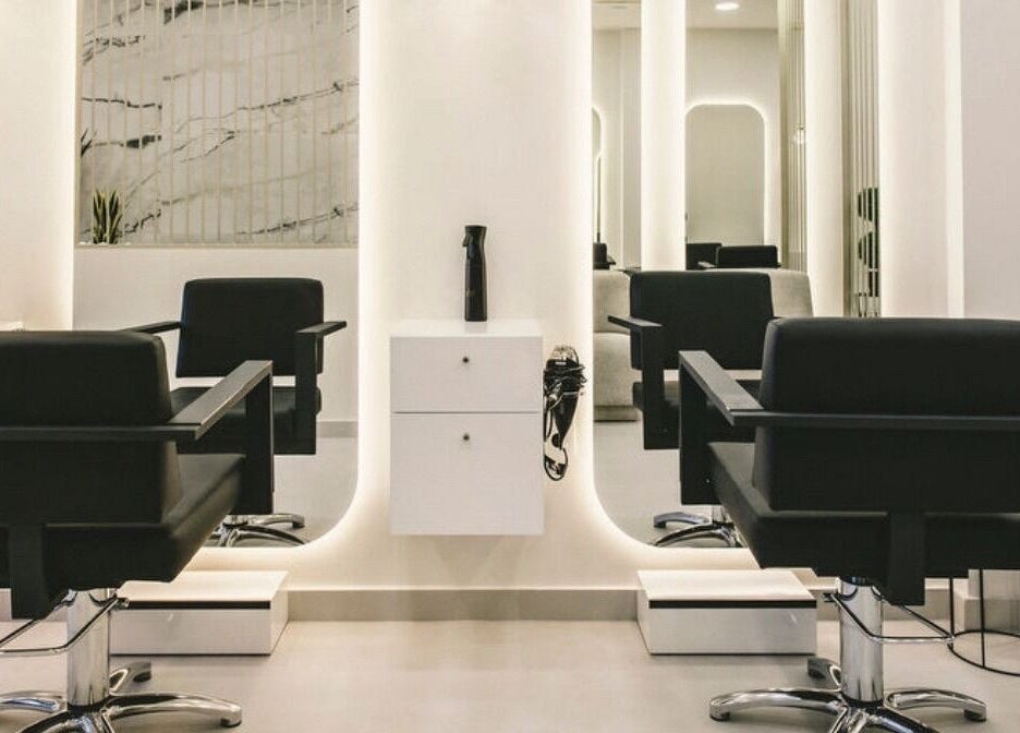 Πολυτελές εσωτερικό του Aliona Moga luxury hair salon στην Αθήνα, GR με κομψά μαύρα καθίσματα και καθρέφτες.