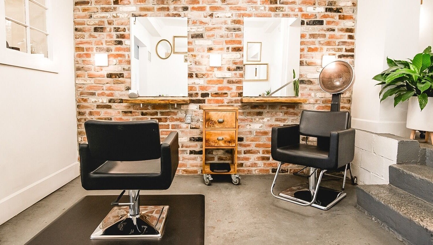 Modern salon chairs at TRiM✂️ Hair Salon + Esthetics, Vancouver, British Columbia, CA with brick wall backdrop.