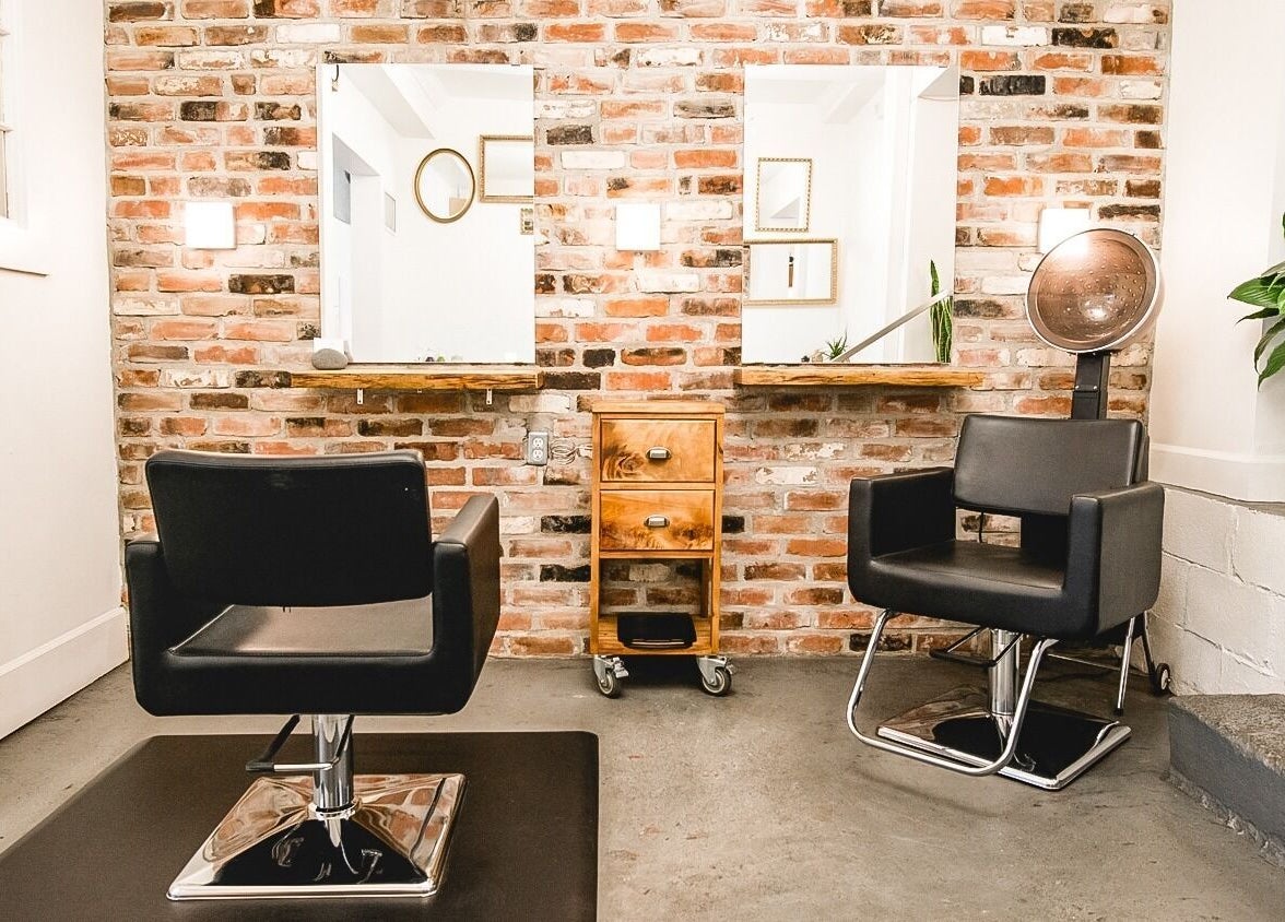Modern salon chairs at TRiM✂️ Hair Salon + Esthetics, Vancouver, British Columbia, CA with brick wall backdrop.