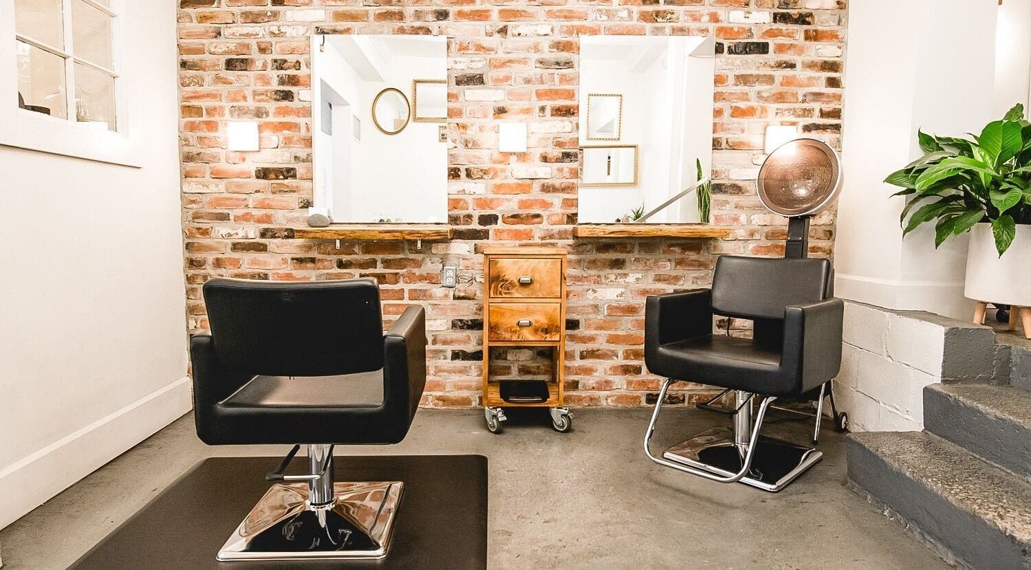 Modern salon chairs at TRiM✂️ Hair Salon + Esthetics, Vancouver, British Columbia, CA with brick wall backdrop.