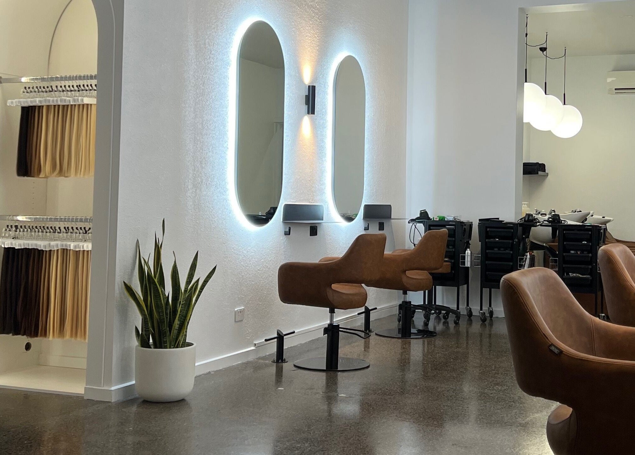Modern salon interior at Hair by Hustle and Co, Richmond, Victoria, AU with sleek chairs and mirrors.