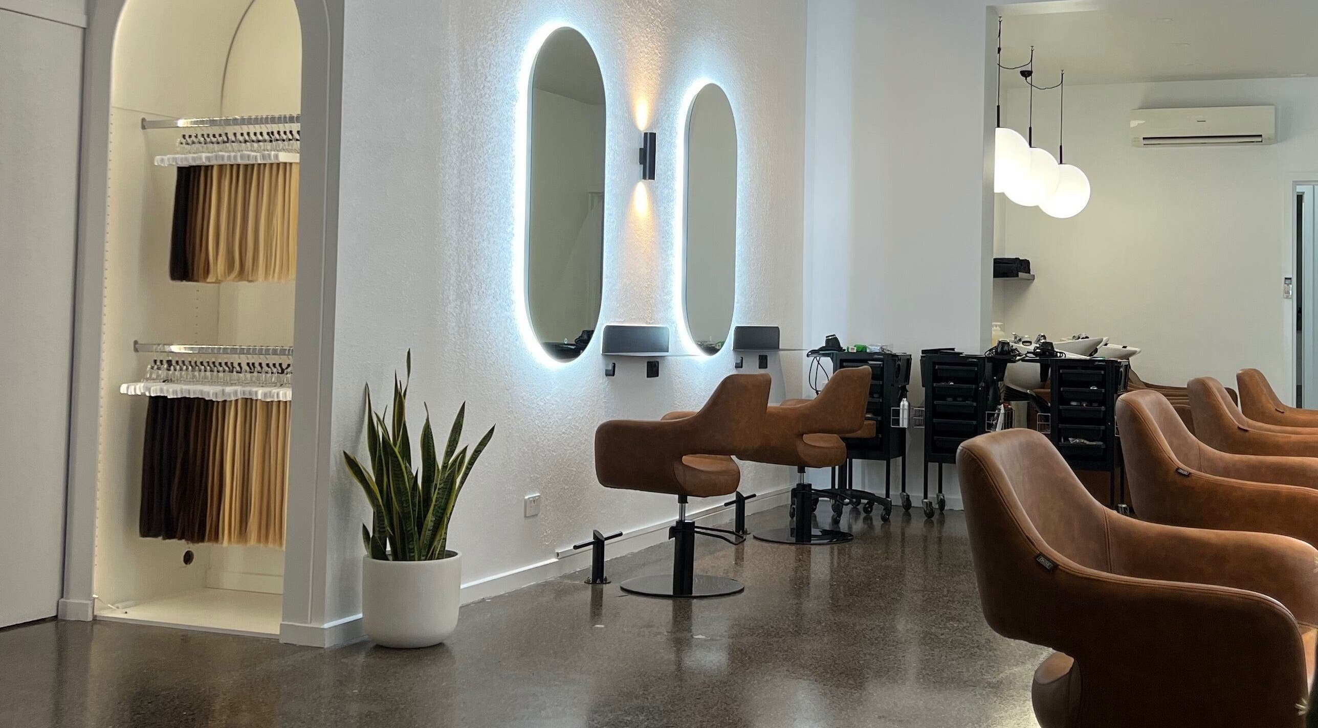 Modern salon interior at Hair by Hustle and Co, Richmond, Victoria, AU with sleek chairs and mirrors.