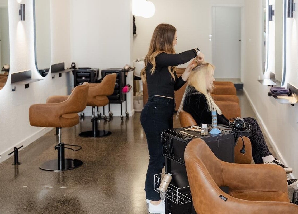 Modern salon interior at Hair by Hustle and Co, Richmond, Victoria, AU showcasing stylist at work.