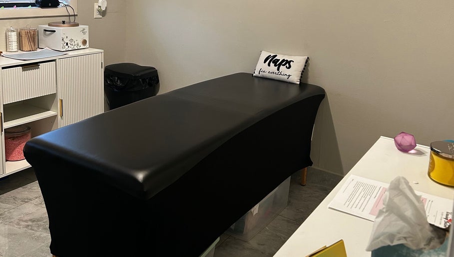 A tranquil waxing treatment room at Waxed by Ky in Fort Myers, Florida, US, with a sleek black treatment bed.