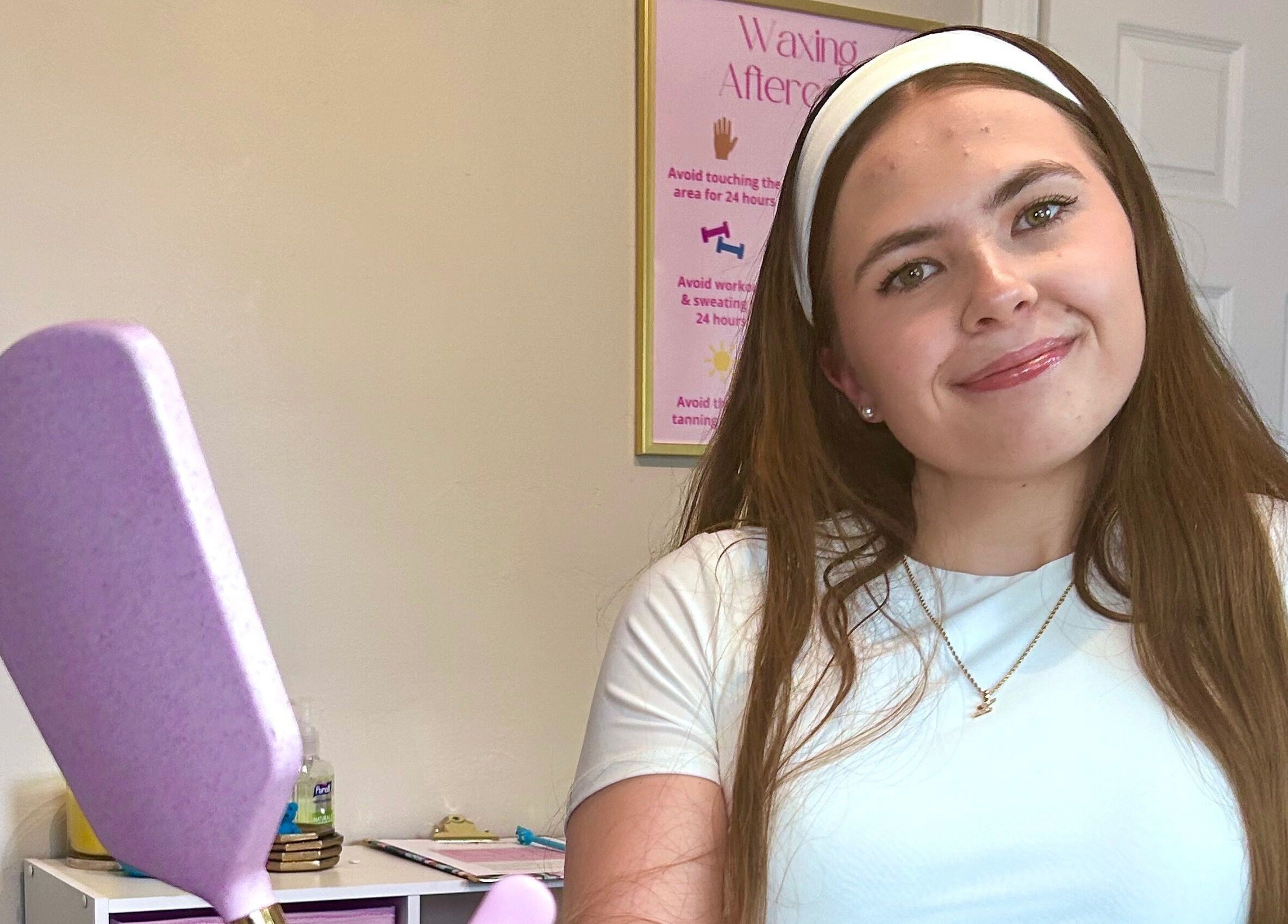 Smiling staff at Waxed by Ky, Fort Myers, Florida, US, with waxing spatula in a welcoming setting.