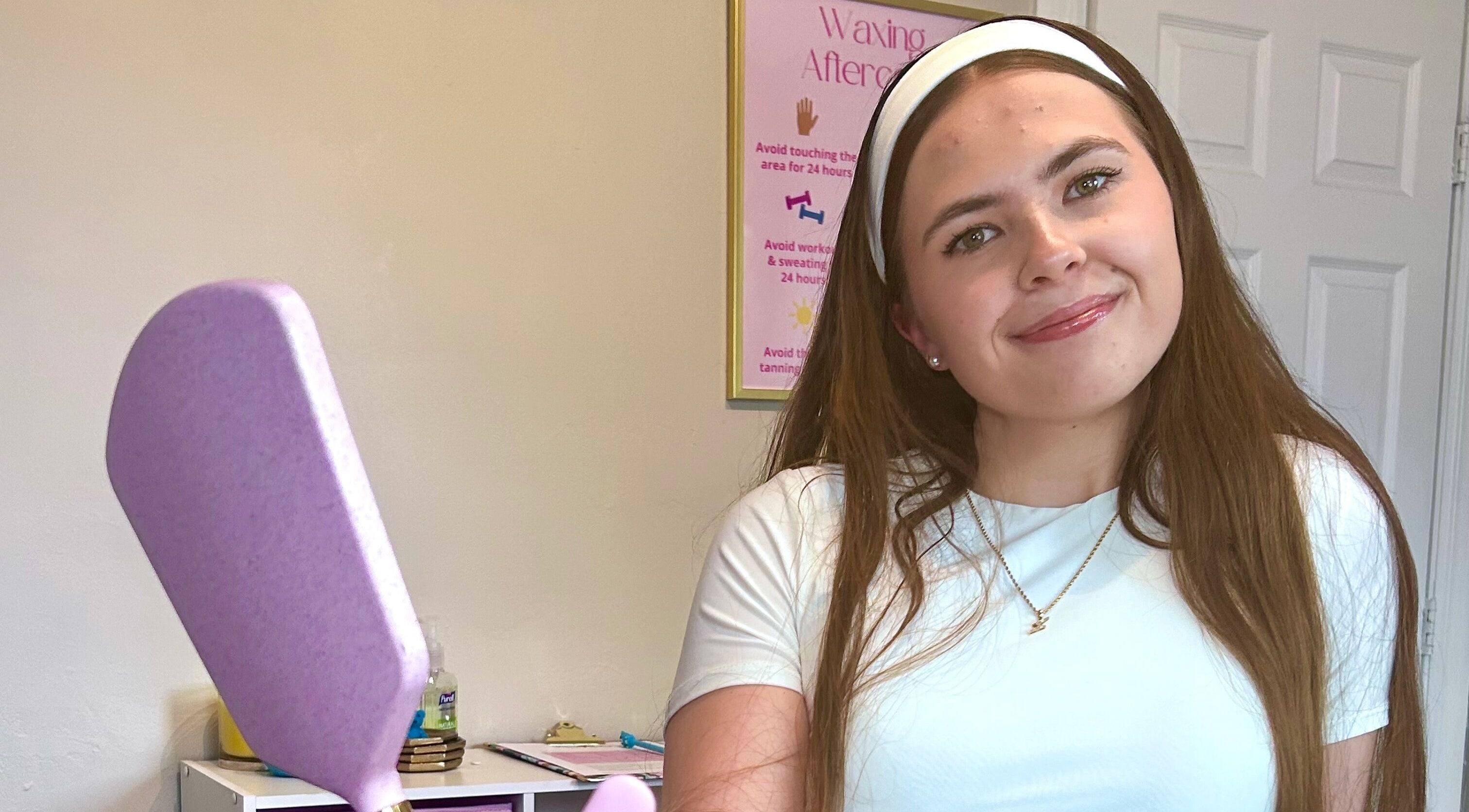 Smiling staff at Waxed by Ky, Fort Myers, Florida, US, with waxing spatula in a welcoming setting.