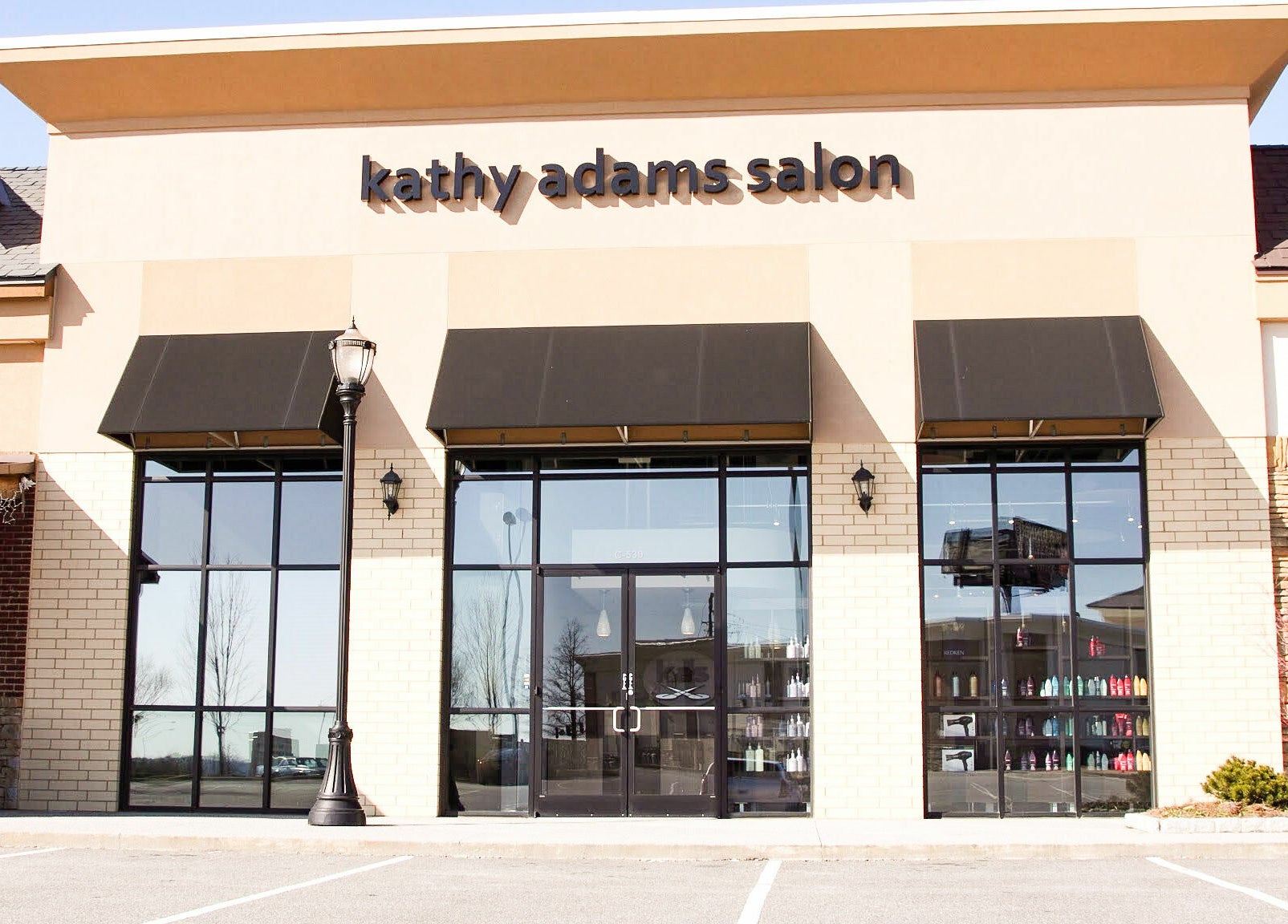Front view of Kathy Adams Salon, Buford, Georgia, US with chic black awnings and large windows.