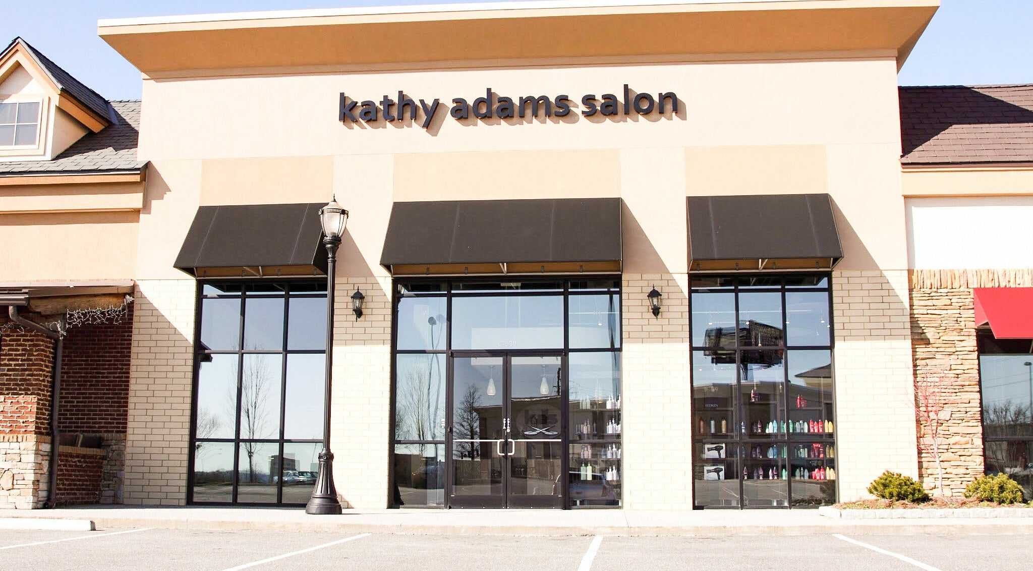 Front view of Kathy Adams Salon, Buford, Georgia, US with chic black awnings and large windows.