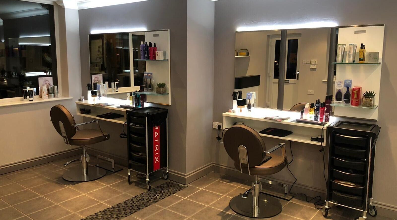 Modern salon setup at Invidia Hair and Beauty, Norwich, England, GB, showcasing styling stations and products.