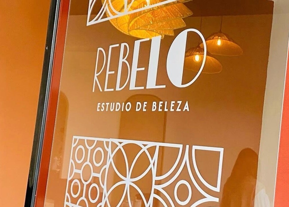 Logo de Rebelo - Estúdio de Beleza na janela, Valongo, Porto, PT. Ambiente interno refletido.