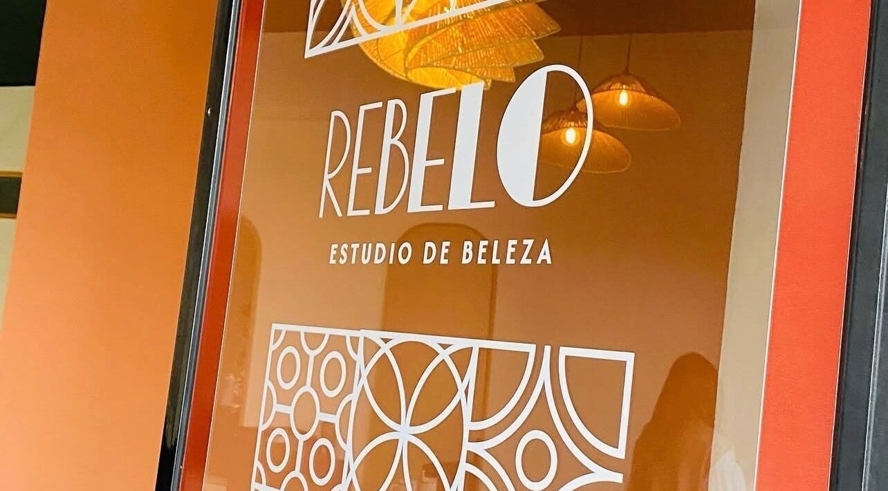 Logo de Rebelo - Estúdio de Beleza na janela, Valongo, Porto, PT. Ambiente interno refletido.