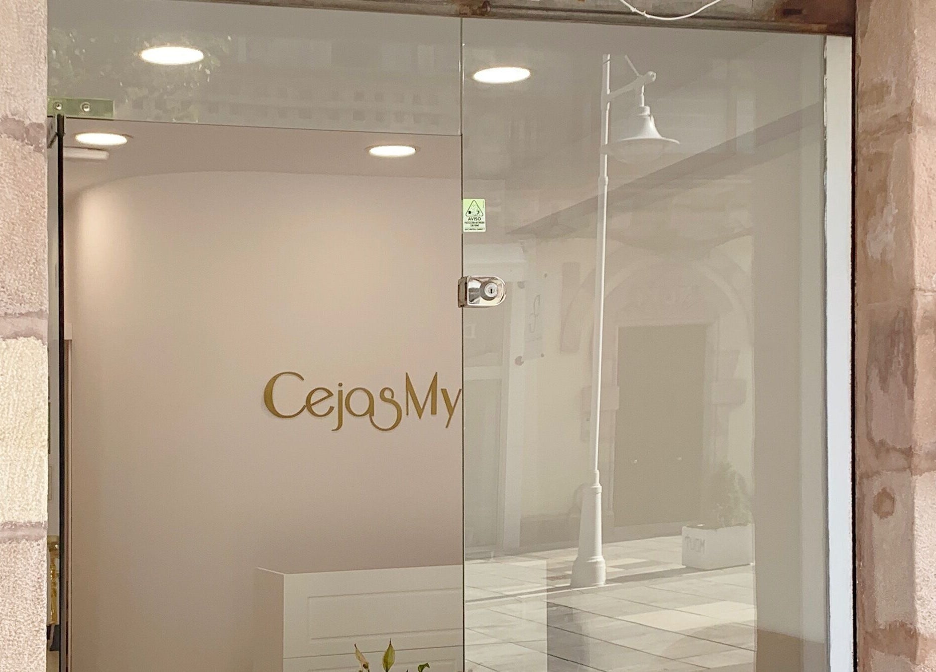Entrada de CejasMy en Torrelavega, Cantabria, ES, mostrando el logotipo dorado en vidrio.