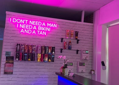 Chic interior of Only Tans in Wickford, England, GB, featuring pink neon lights and tanning products displayed.