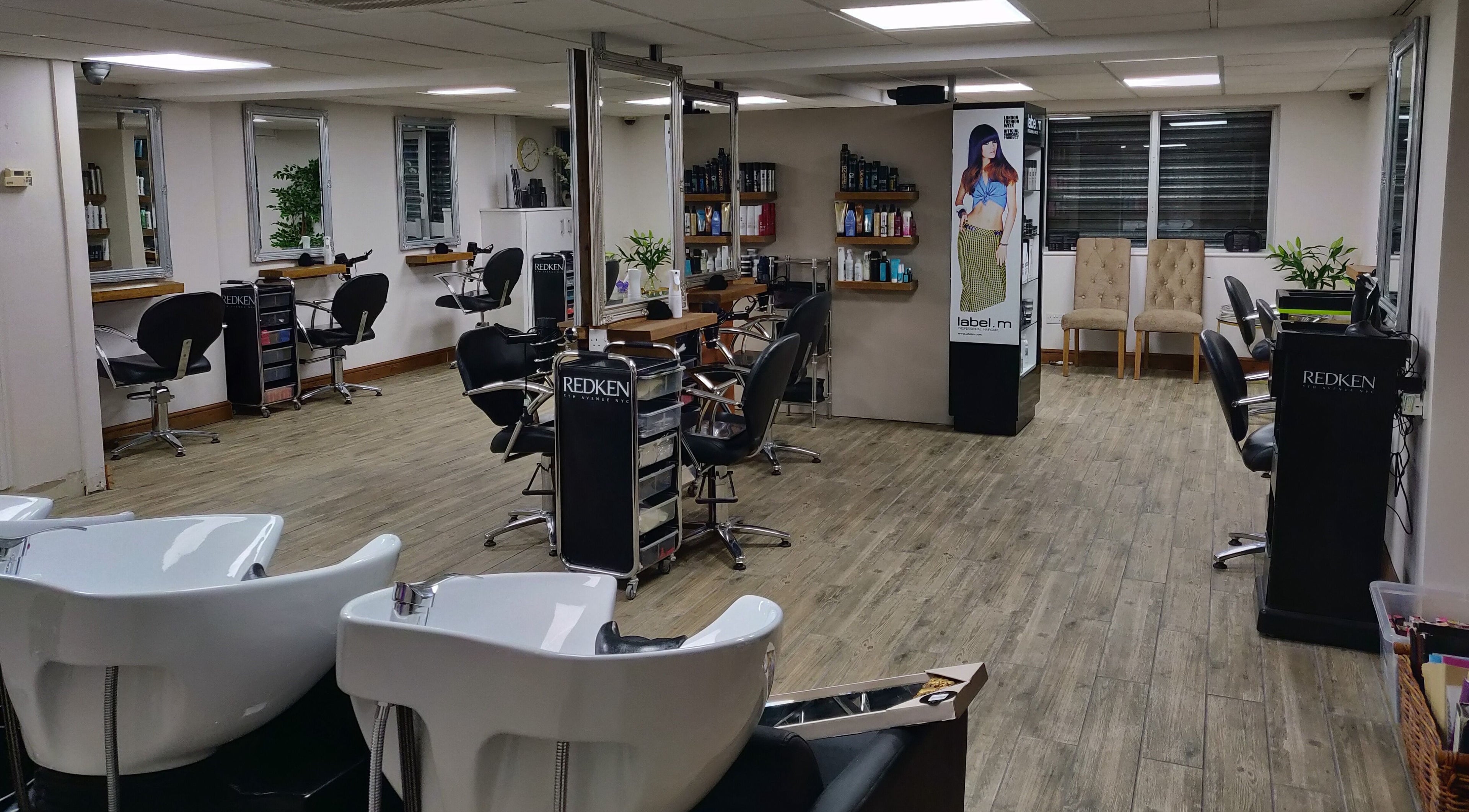 Chic interior of Mane Creations salon in Colchester, England, GB featuring workstations and vibrant decor.