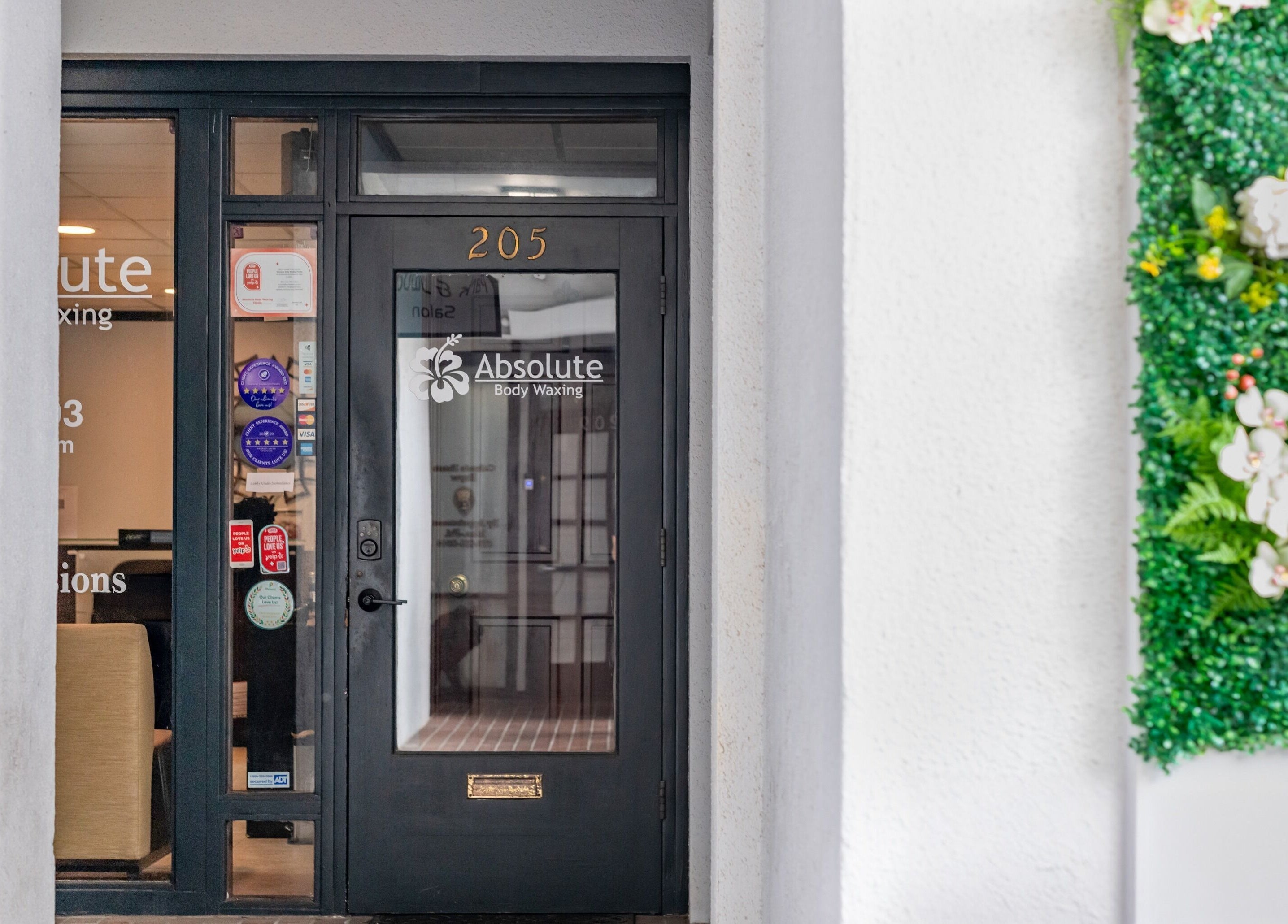 Entrance of Absolute Body Waxing and Spa adorned with greenery, located in Winter Park, Florida, US.