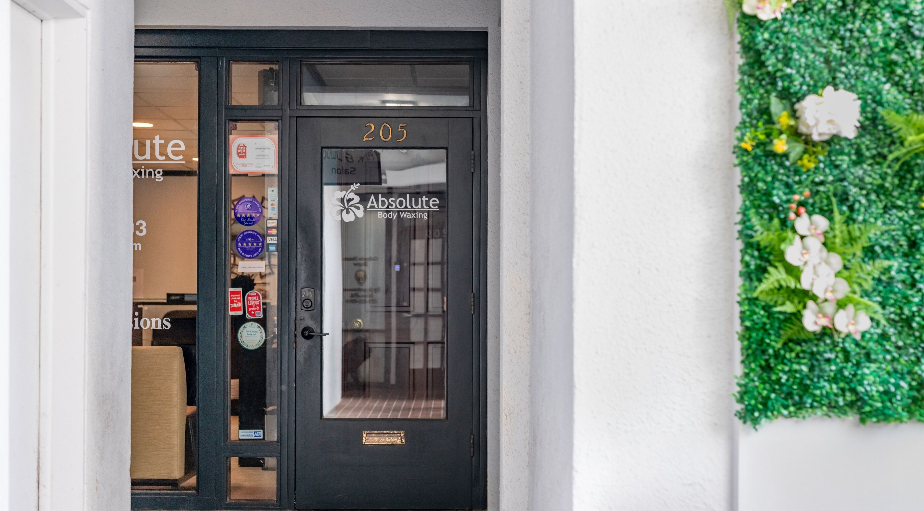 Entrance of Absolute Body Waxing and Spa adorned with greenery, located in Winter Park, Florida, US.