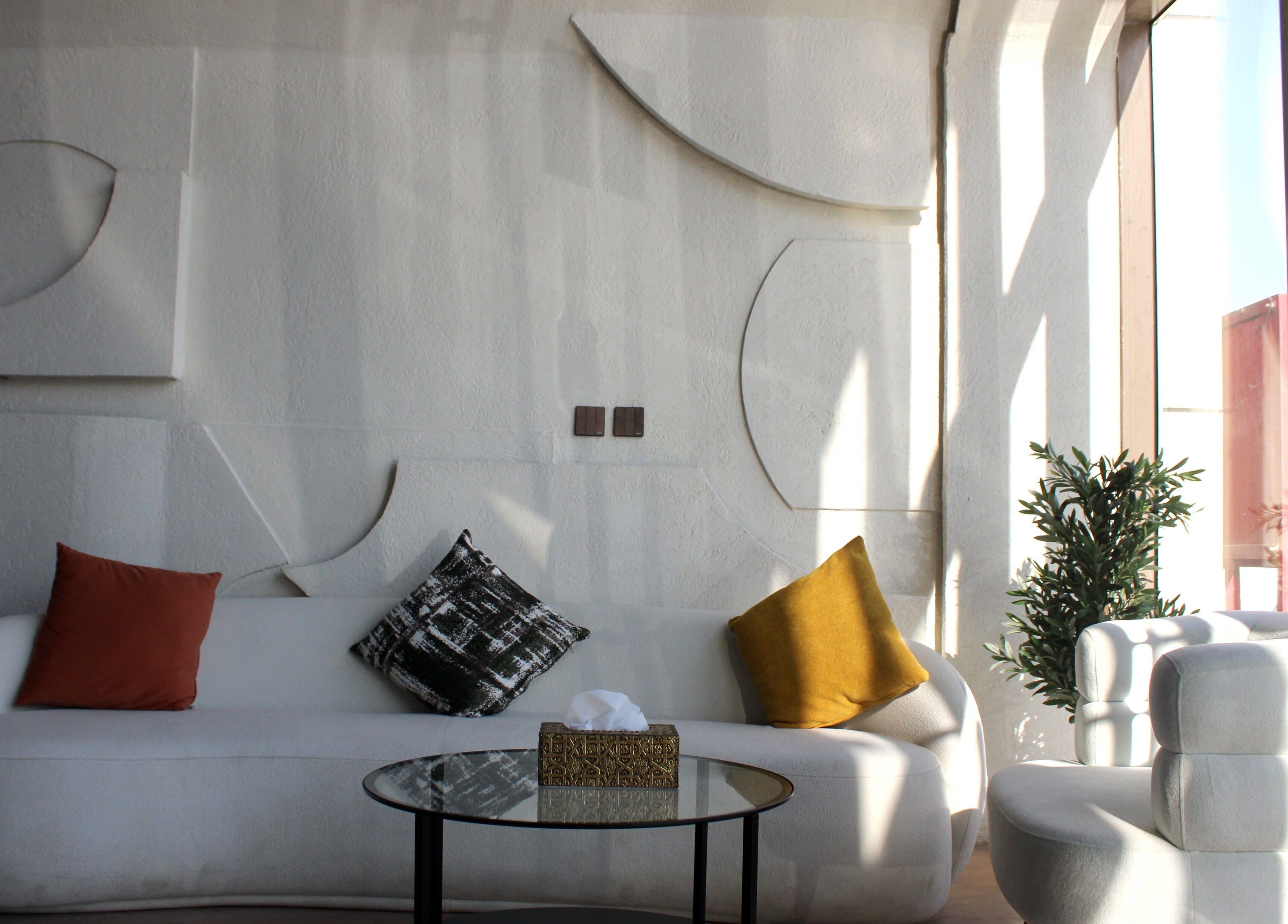 منطقة جلوس حديثة في سان سبا، الرياض، الرياض، السعودية، مع أرائك بيضاء ووسائد ملونة ونباتات.